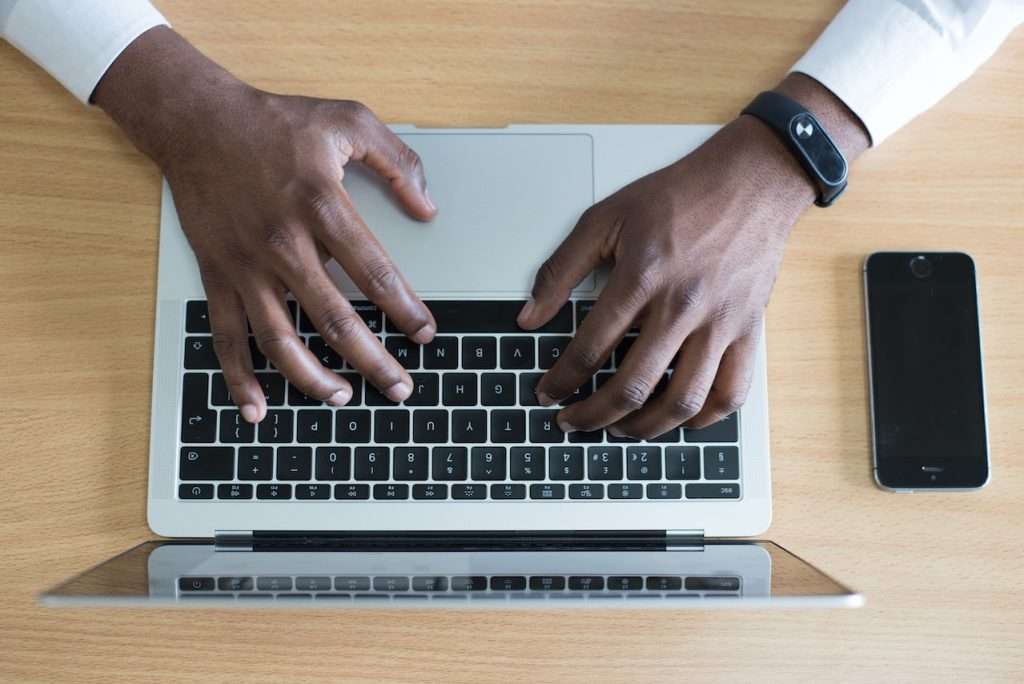 black man typing mail on laptop